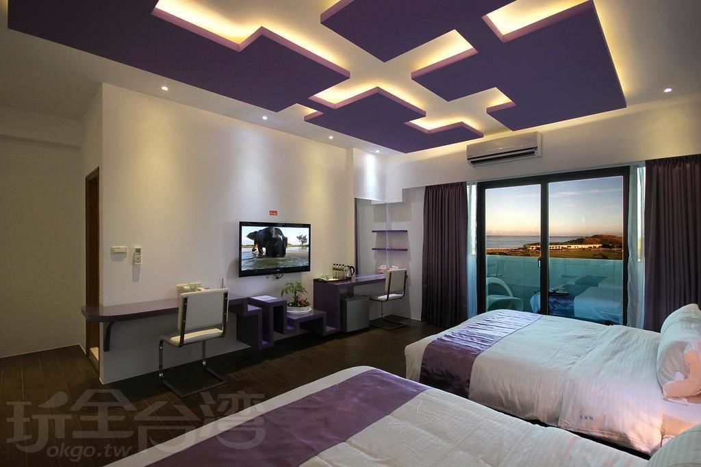 Una habitación de hotel moderna con una cama grande, un escritorio, un televisor y un balcón con vista a la ciudad.