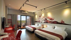 Une chambre d’hôtel avec deux lits, un coin repas avec des chaises rouges, une grande fenêtre donnant sur un beau paysage et un tableau accroché au mur.