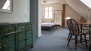 Ein Zimmer mit einem Bett, einem Schminktisch, einem Esstisch mit Stühlen und einem großen Spiegel.
