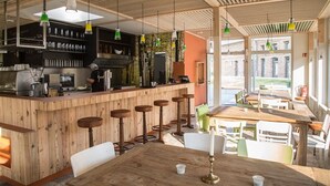 Un restaurant doté d’un bar en bois, de tabourets hauts et offrant une vue sur l’extérieur.