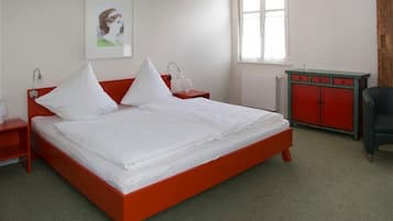 A bed with a red frame, white bedding, and two bedside tables with lamps.