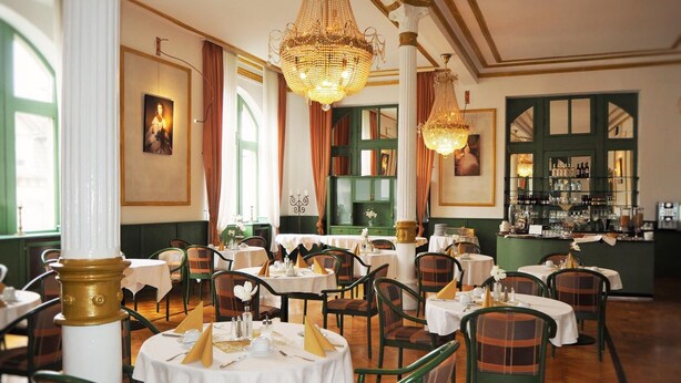 A restaurant with round tables, green chairs, and chandeliers. - Gala Hotel (Pforzheim)
