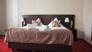 A neatly made bed with a brown bedspread, two pillows, and two bedside lamps.