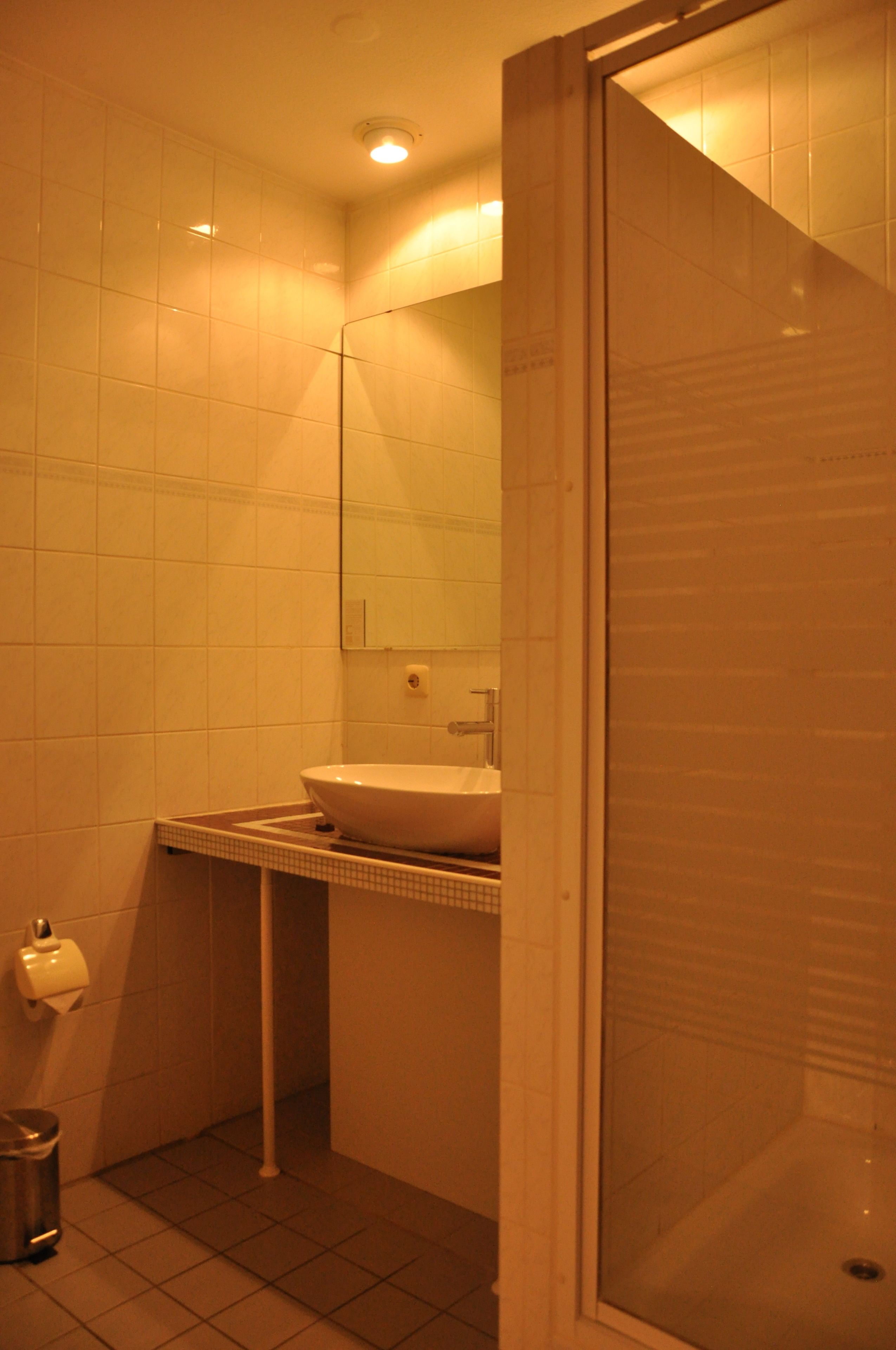 A bathroom with a white sink, a mirror, and a toilet.