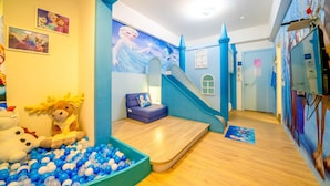 Zona infantil con piscina de pelotas, tobogán y un mural de paisaje nevado.