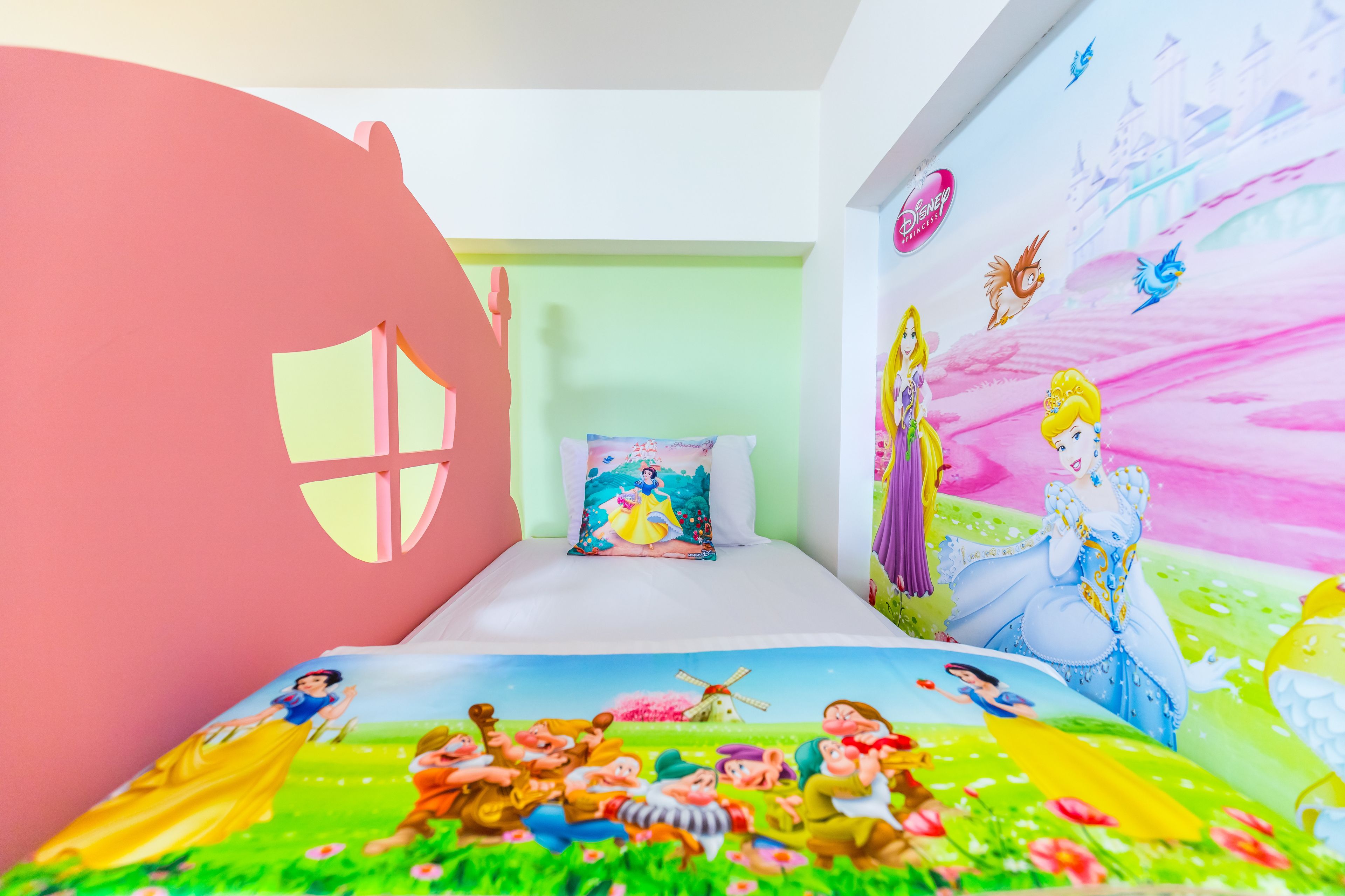 A children's bedroom with Disney-themed decorations, including a mural and bedding.