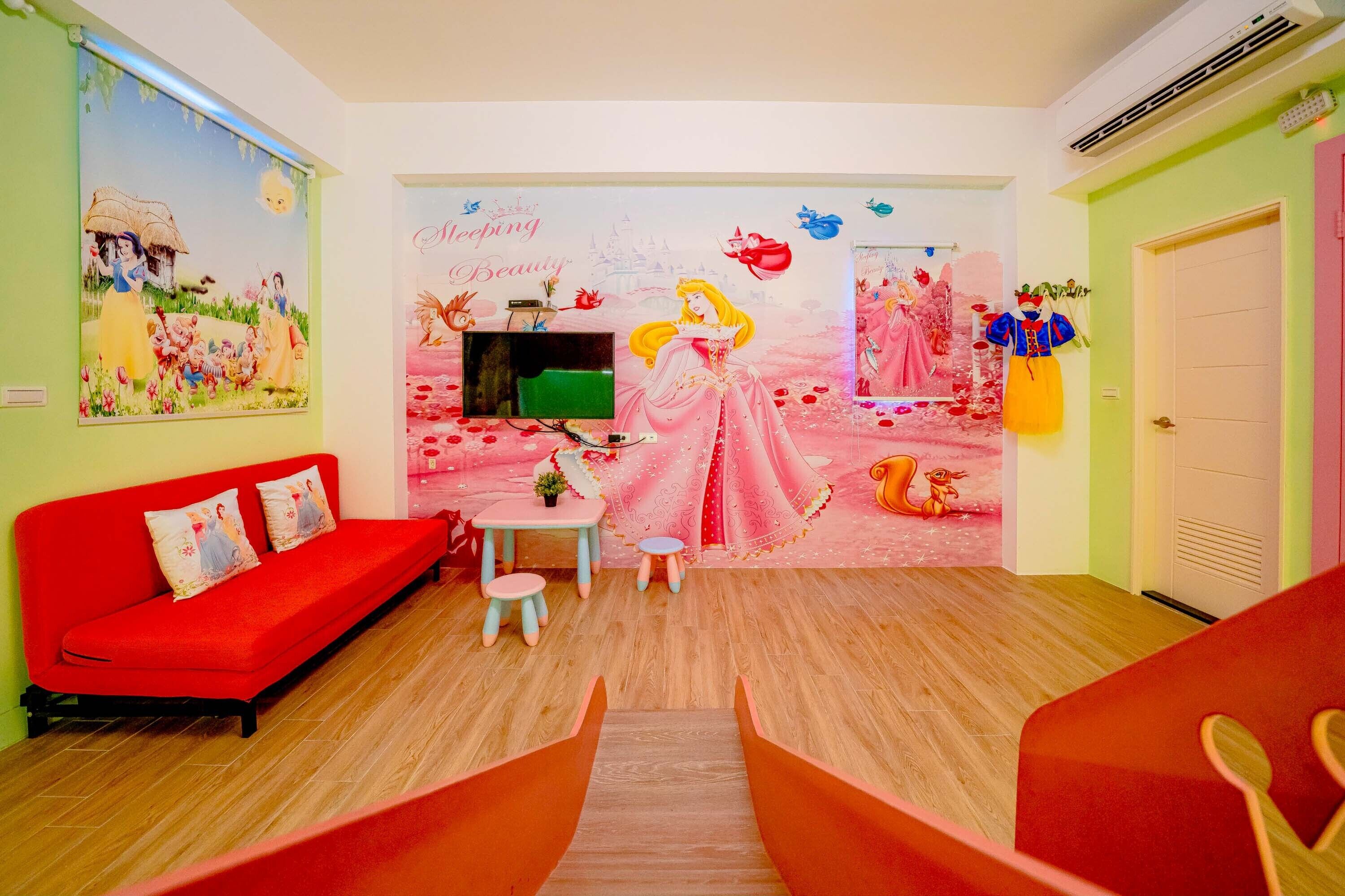 Ein Zimmer mit einer roten Couch, einem kleinen Tisch und einer Wandmalerei.