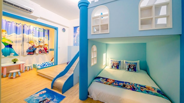 Una habitación infantil con una cama temática de castillo, una zona de juegos con un tobogán y una ventana con vistas al exterior.