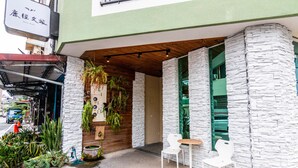 Café com fachada de pedra, teto de madeira e mesas externas com cadeiras brancas.