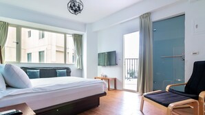 Quarto de hotel moderno com cama, poltrona, televisão e varanda.