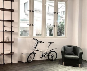 Relax in a serene space with a view of the residential area, featuring a comfortable armchair and a stylish shelving unit.