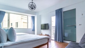 Quarto moderno com uma cama grande, um sofá, uma TV e uma porta de vidro deslizante para uma varanda.