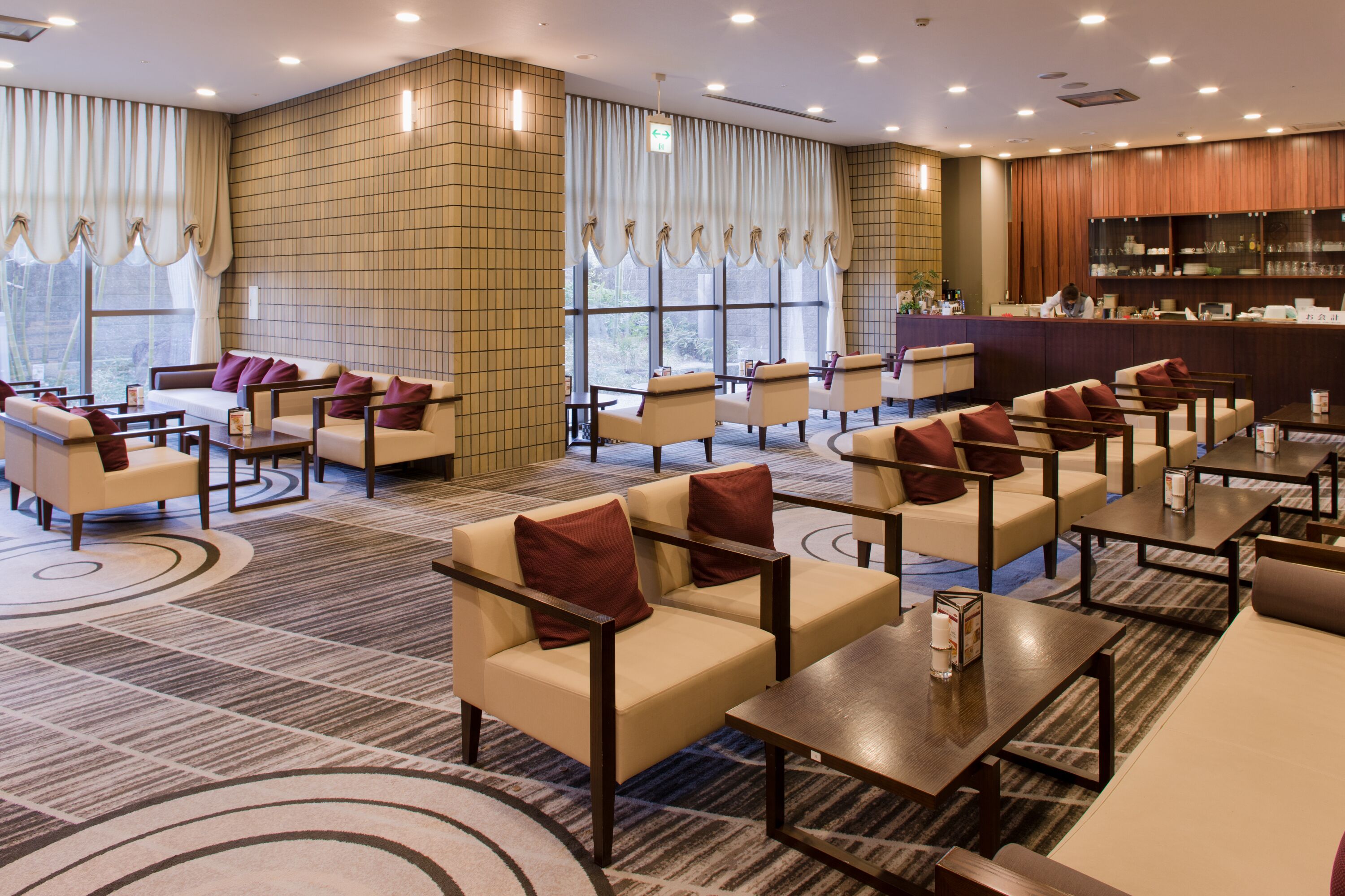 Eine Hotellobby mit Sitzbereichen, einer Rezeption und einer Bar.