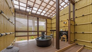 Een traditioneel Japans onsen met een warmwaterbron, houten vloeren, bamboe wanden en uitzicht op de natuur.