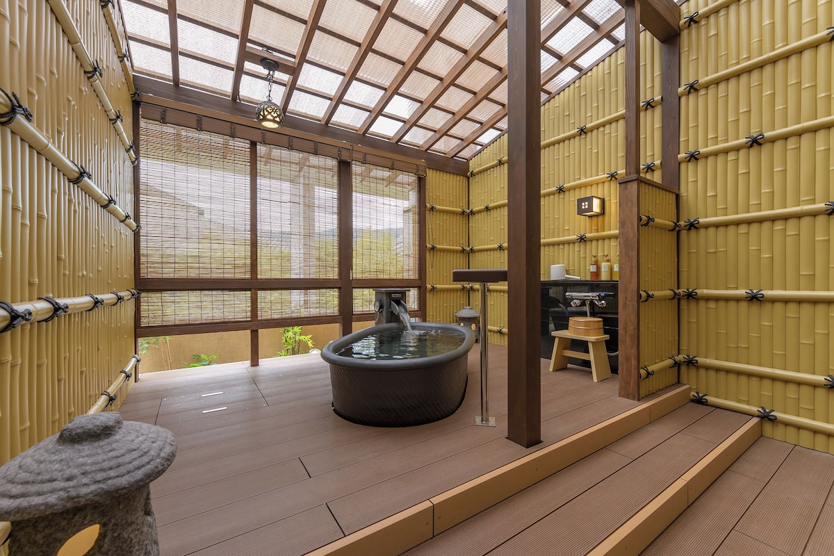 Ett traditionellt japanskt onsen med en varm källa, trägolv, bambuväggar och utsikt över naturen.