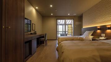 A hotel room with two beds, a desk, and a TV.