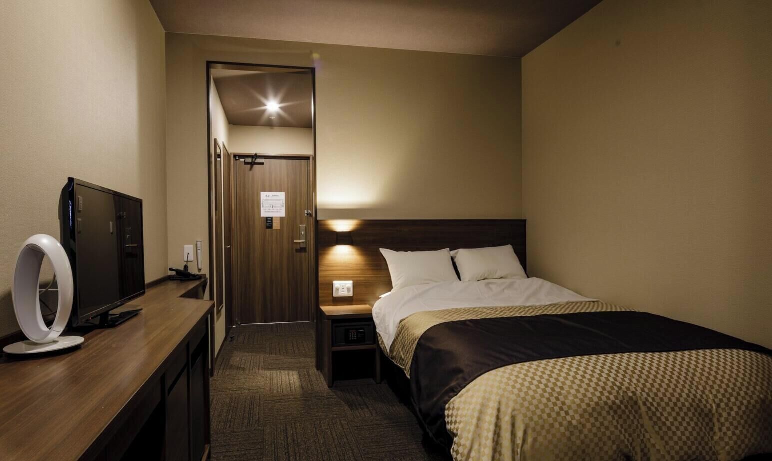 Ein Hotelzimmer mit Bett, Nachttisch, Fernseher und einem Ringlicht.