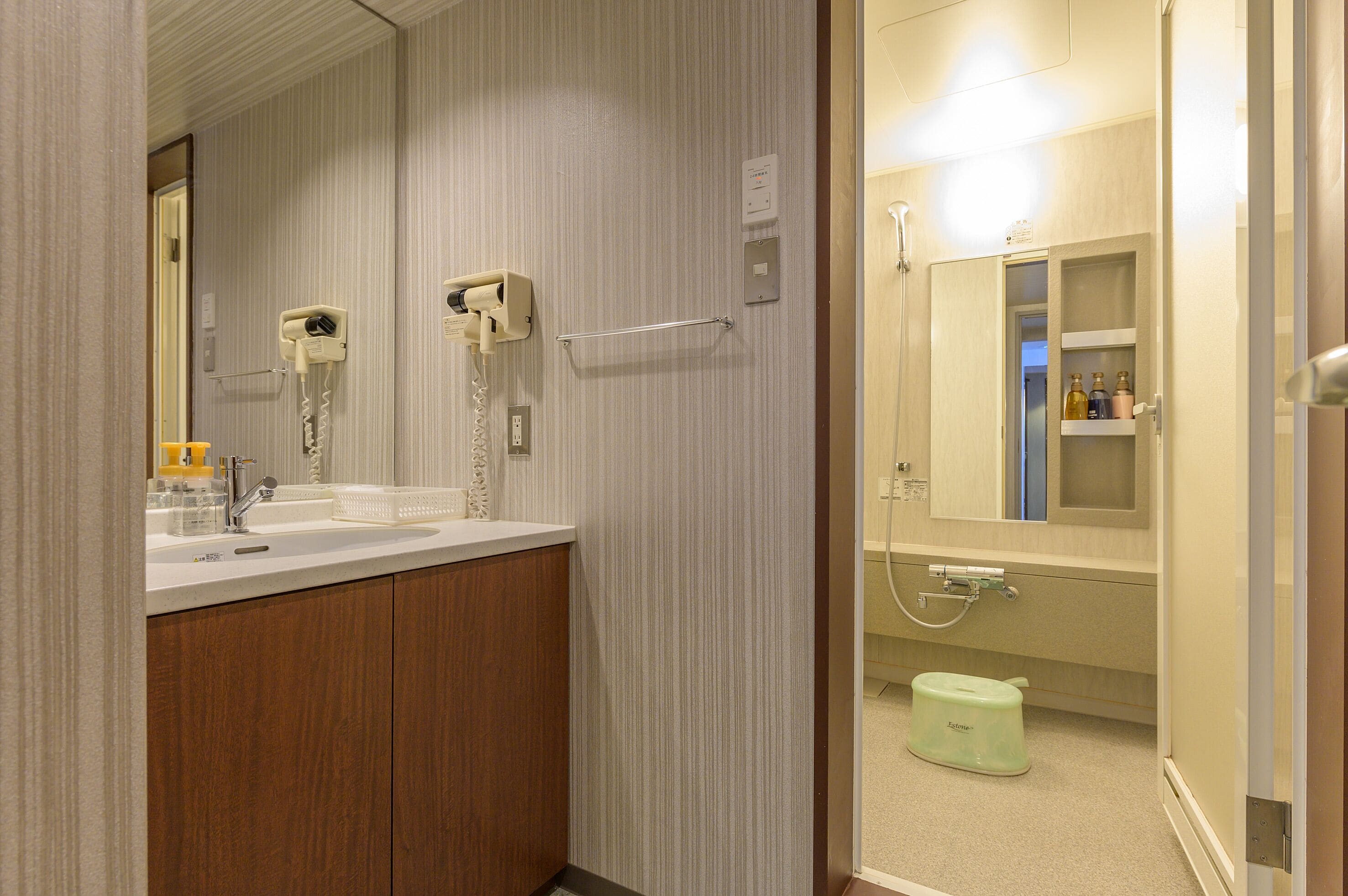 A bathroom with a sink, mirror, towel rack, and a shower area with a toilet.