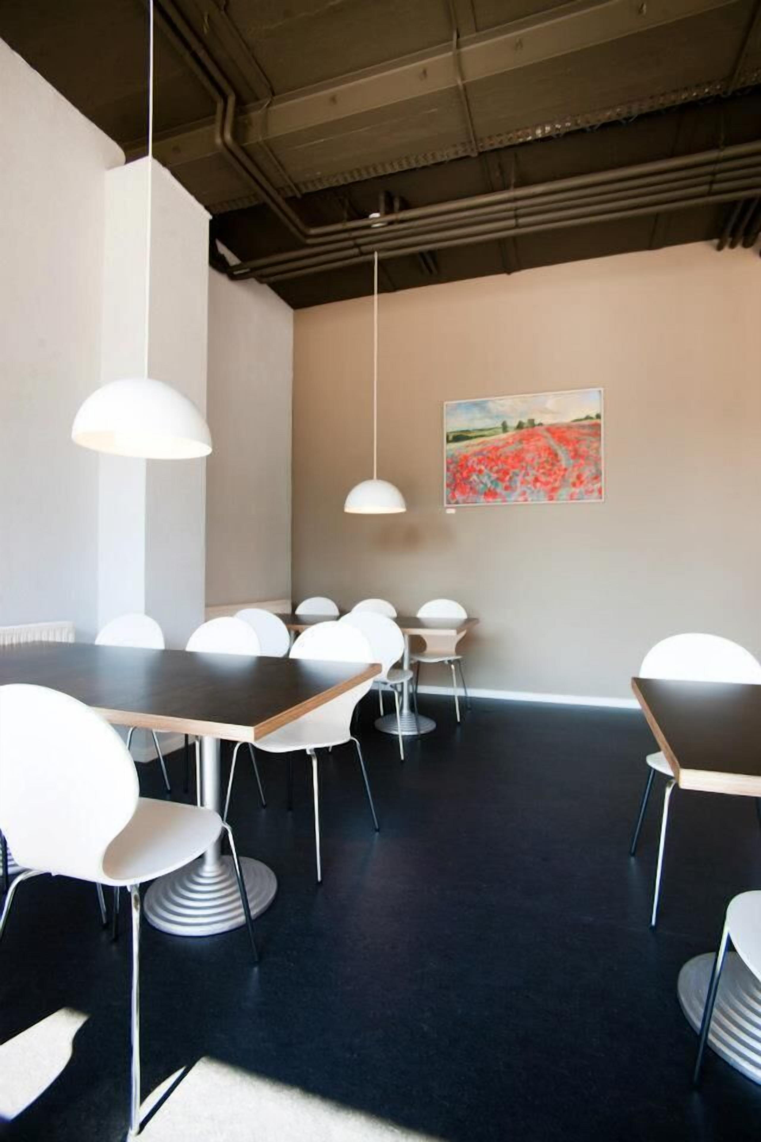 A conference room with a dark floor, white chairs, a long table, and pendant lights.