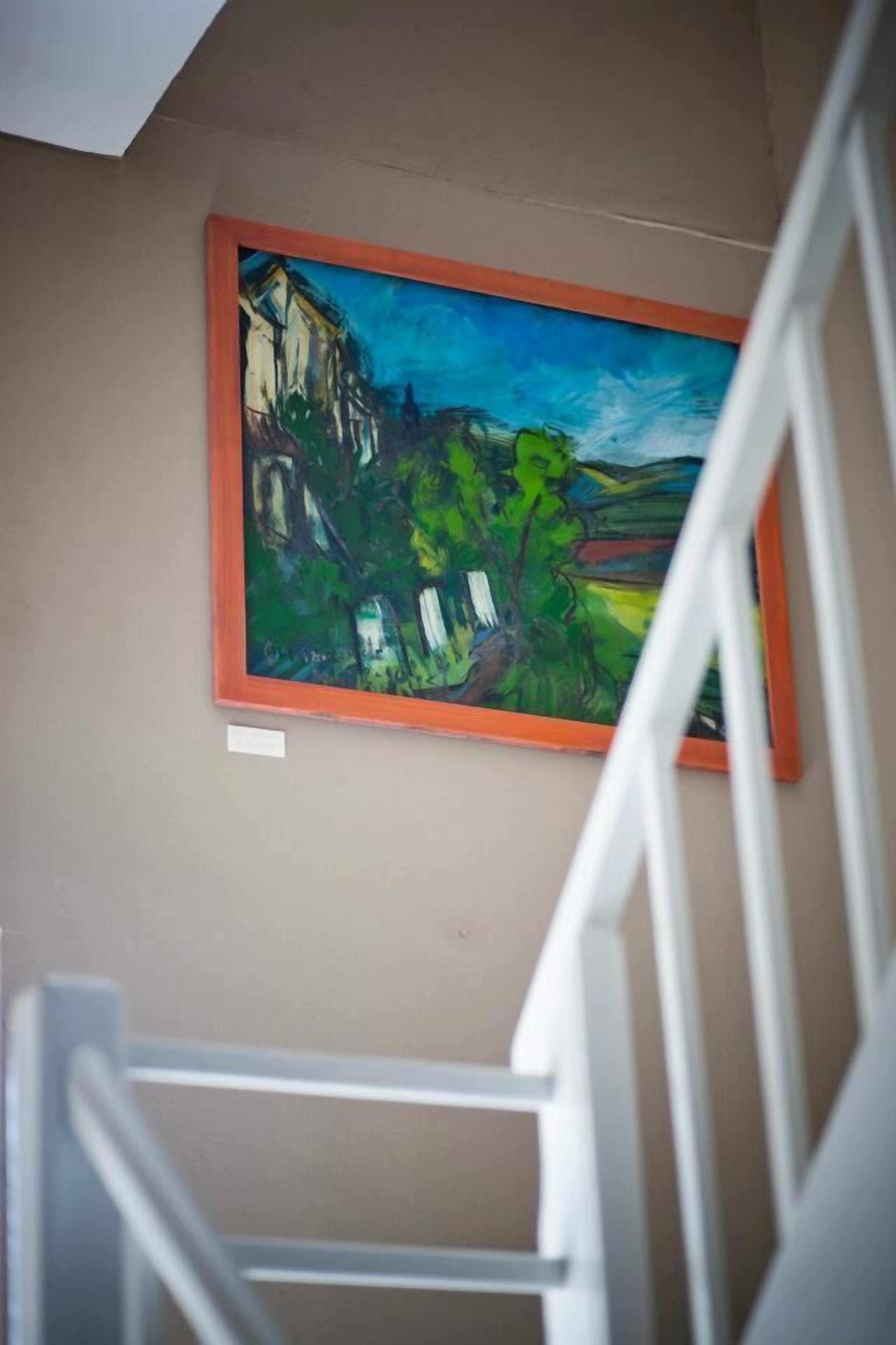 A painting of a landscape with buildings and trees on a wall.