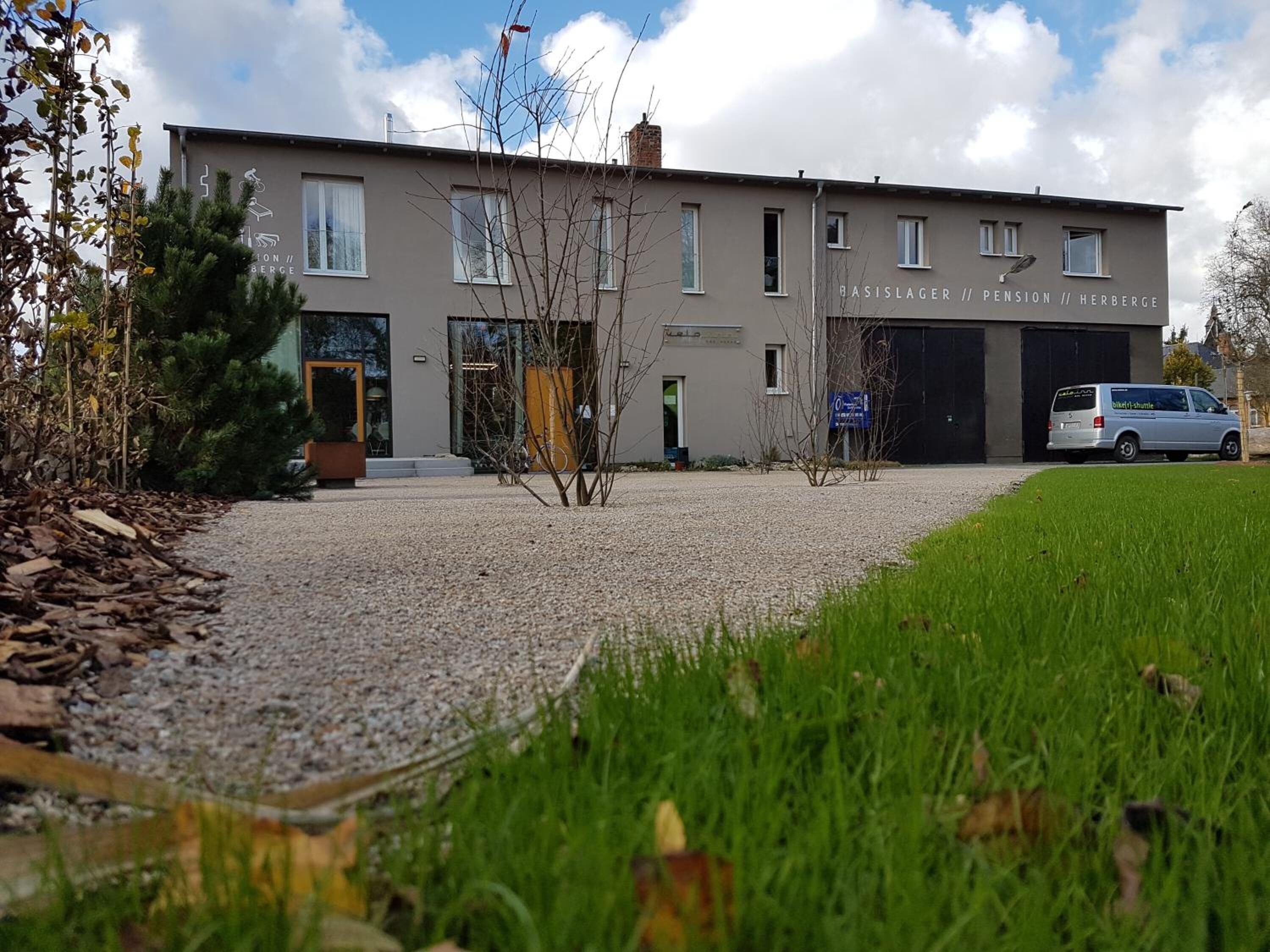 A modern building with a gravel driveway and a parked van.