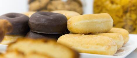 Un plato de donas variadas con glaseado de chocolate y azúcar.