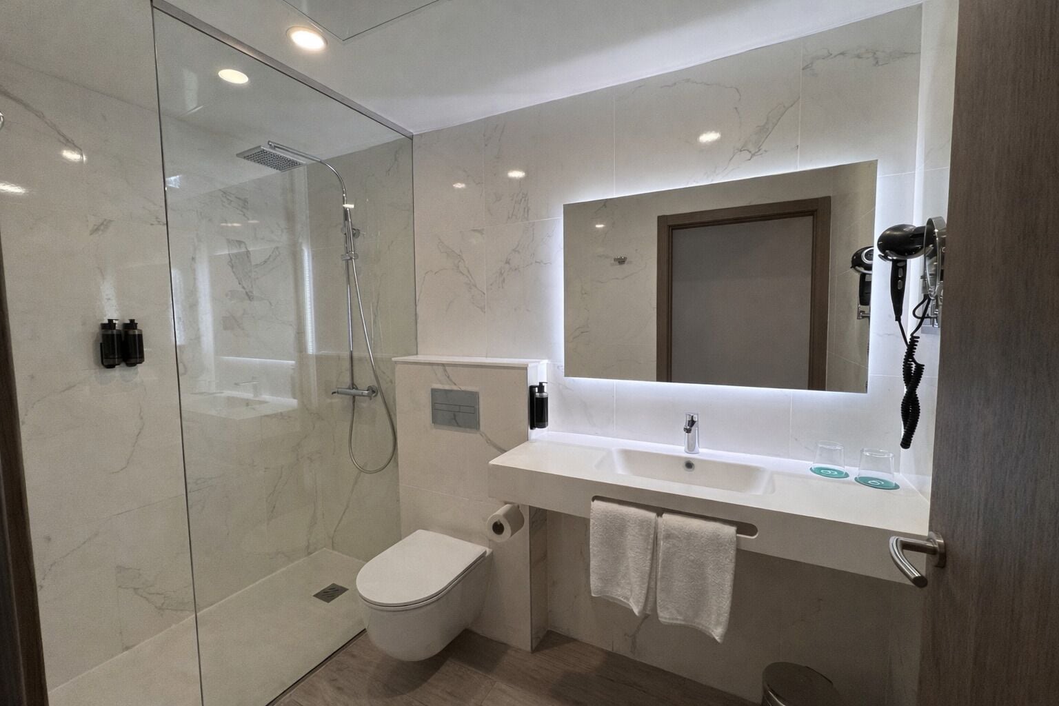 A modern bathroom with a glass-enclosed shower, a toilet, and a vanity with a mirror.