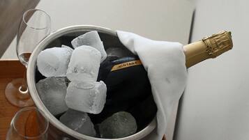 A bucket containing a bottle of champagne, ice cubes, and two empty wine glasses.