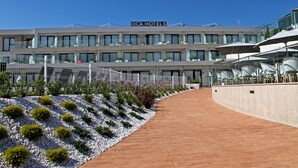 Un hotel de diseño moderno, con un llamativo letrero 'OCA HOTELS' y un espacio exterior bien cuidado que incluye un camino y un jardín ajardinado.