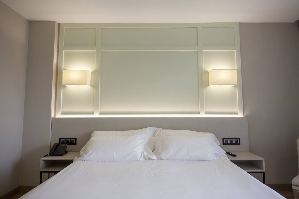 A hotel room with a large bed, two bedside tables, a desk, and a chair.