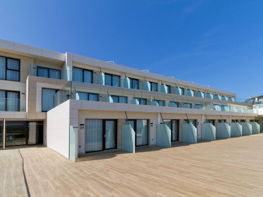 A modern hotel with a flat roof, large windows, and a wooden deck.