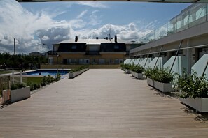 Un edificio moderno con una terraza de madera que conduce a una zona de piscina.