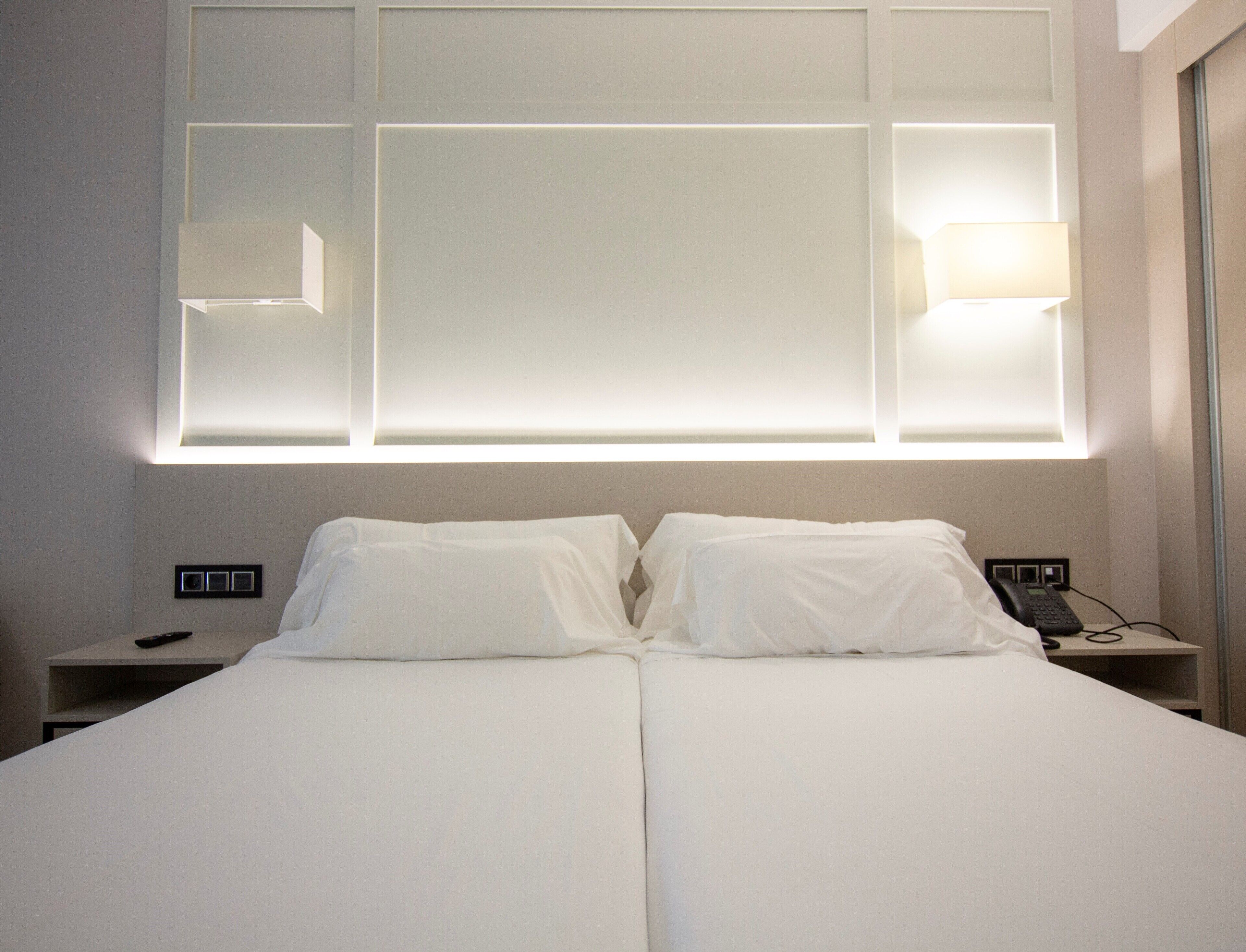 Een hotelkamer met een groot bed, twee bedlampen, een bedtelefoon en een nachtkastje.