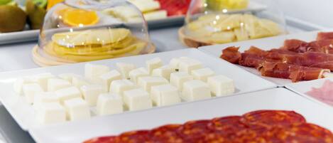 Un buffet proposant une variété d’aliments, notamment des fromages, des charcuteries et des fruits.