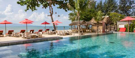 Una piscina al aire libre, sombrillas, sillones reclinables de piscina