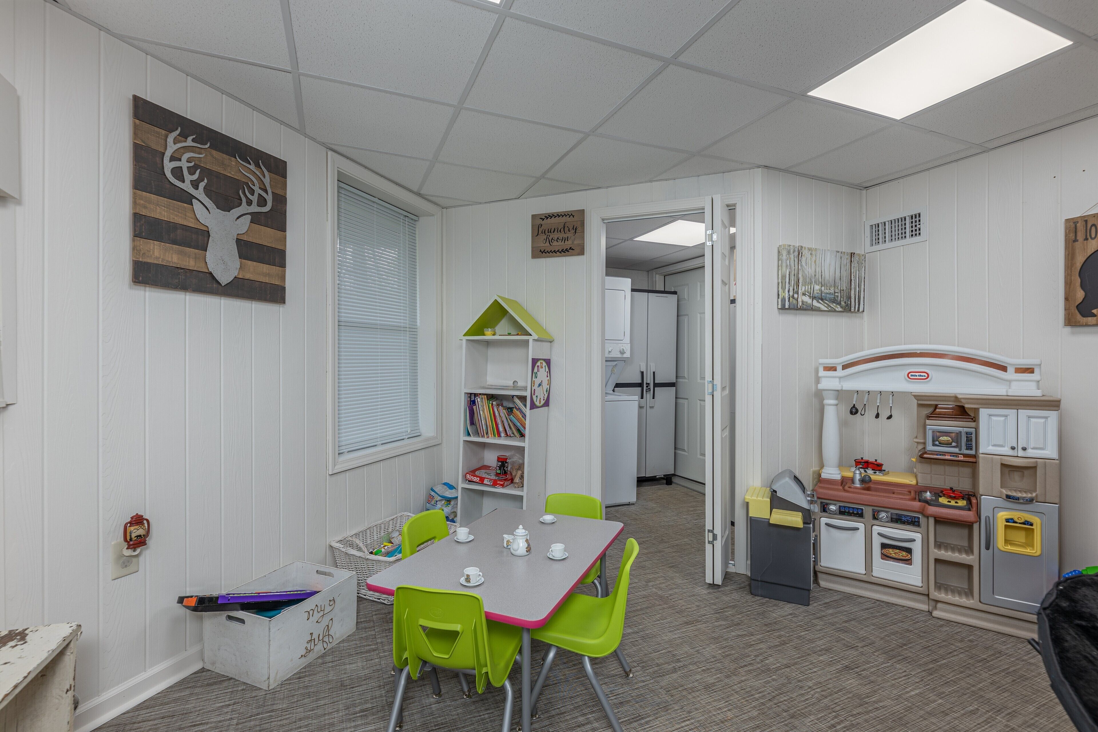 Une salle de jeux pour enfants avec une table, des chaises et une cuisine miniature.