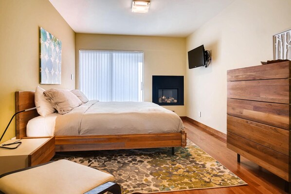 Un dormitorio con cama, mesita de noche, lámpara y chimenea.