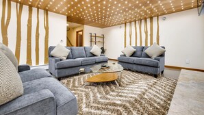 Un salon moderne avec deux canapés gris, une table basse en verre et un tapis à motifs.