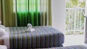 Ein Hotelzimmer mit zwei Betten, gestreifter Bettwäsche und einem schwanenförmigen Kissen auf jedem Bett.