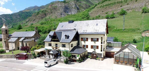 A hotel with a central building, a bell tower, and a greenhouse. - Hotel Edelweiss (Naut Aran)