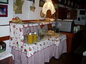 A buffet table with various food items and drinks, surrounded by a checkered tablecloth. - Hotel Edelweiss (Naut Aran)