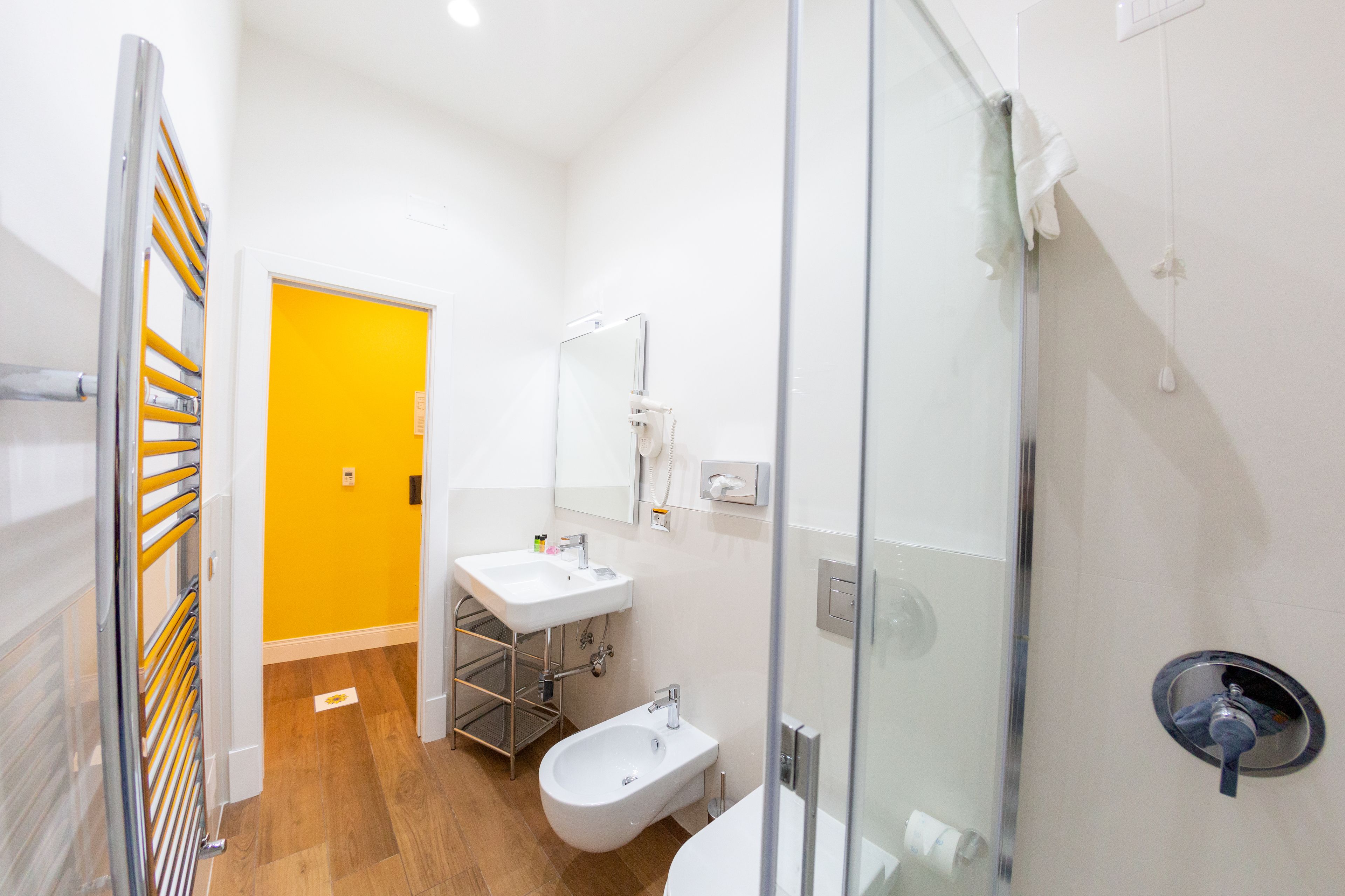 A modern bathroom with a glass shower enclosure, a white sink, and a bidet.