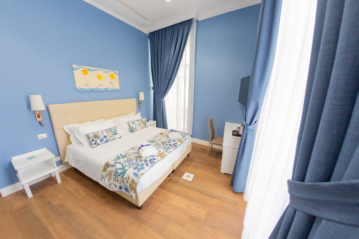 Un dormitorio con cama, mesitas de noche, escritorio y televisor.