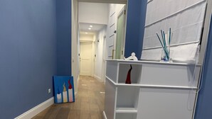 Un pasillo con un sendero estampado, un estante blanco y una pared azul.