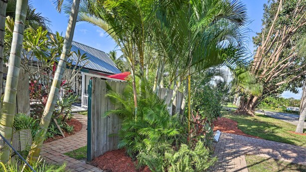 A garden area with a pathway, bamboo plants, and a small shed with a red roof. - Stuart Apartment w/ Patio Near St Lucie River! (Stuart)