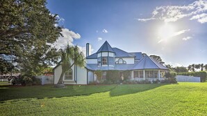 A large house with a prominent tower, a well-maintained lawn, and a clear sky. - Stuart Apartment w/ Patio Near St Lucie River! (Stuart)