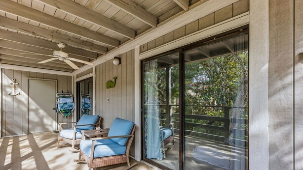 Eine überdachte Terrasse mit Korbstühlen und einem Deckenventilator.