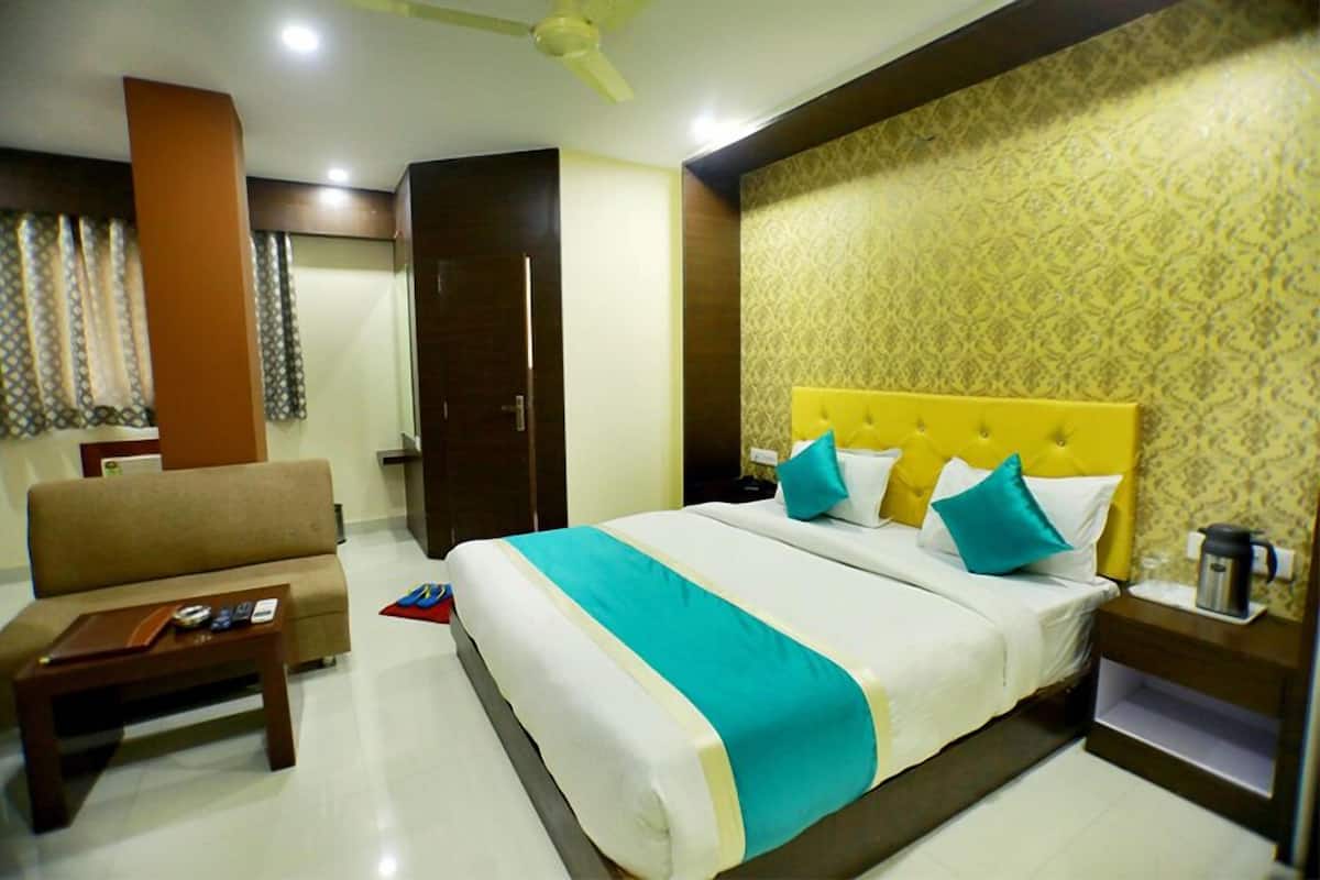 Quarto de hotel com cama, sofá, mesa de centro e mesa de cabeceira.