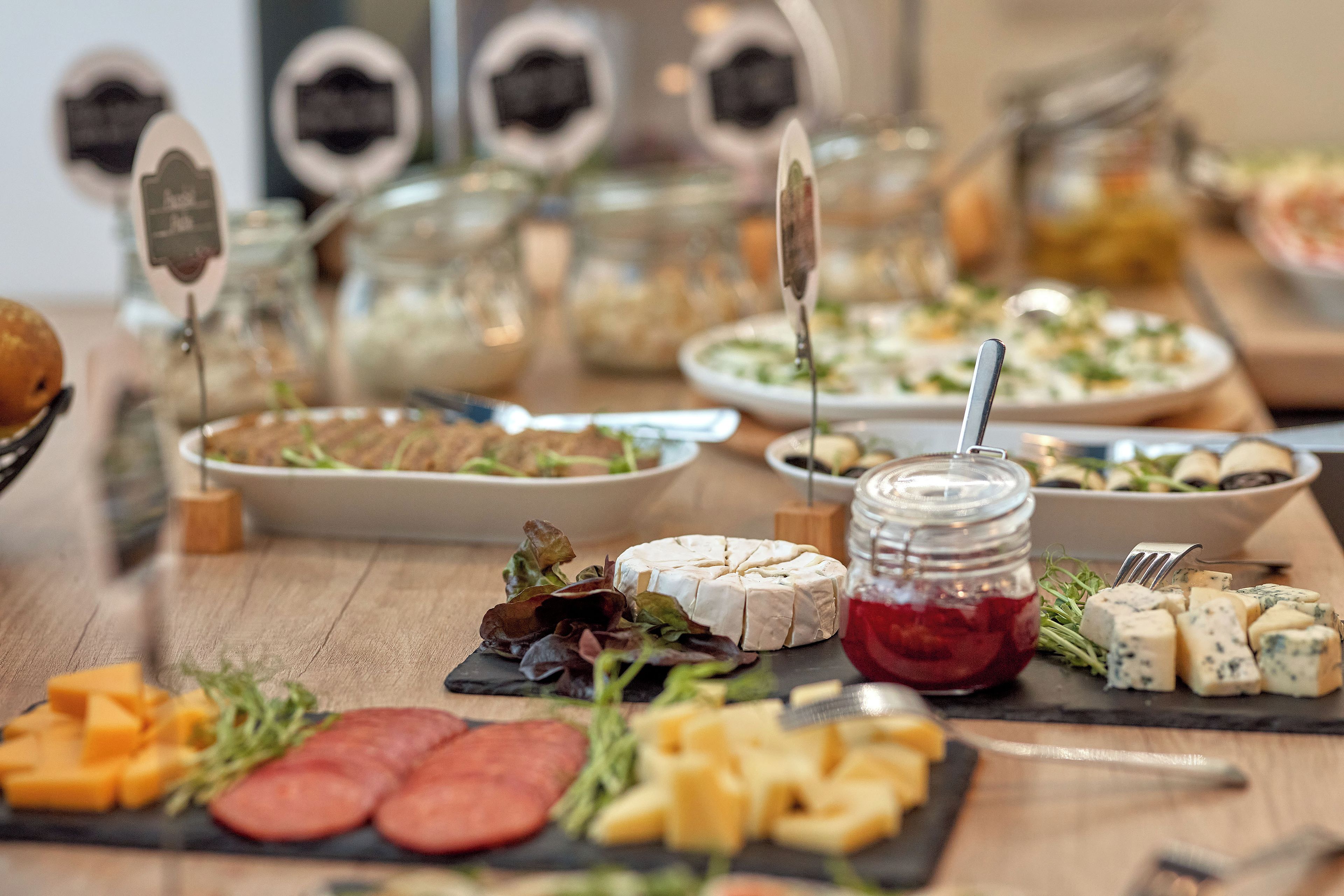 A buffet table with various cheeses, meats, and salads.