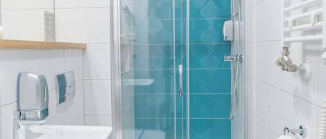 A modern bathroom with a glass shower enclosure, a white sink, and a toilet.
